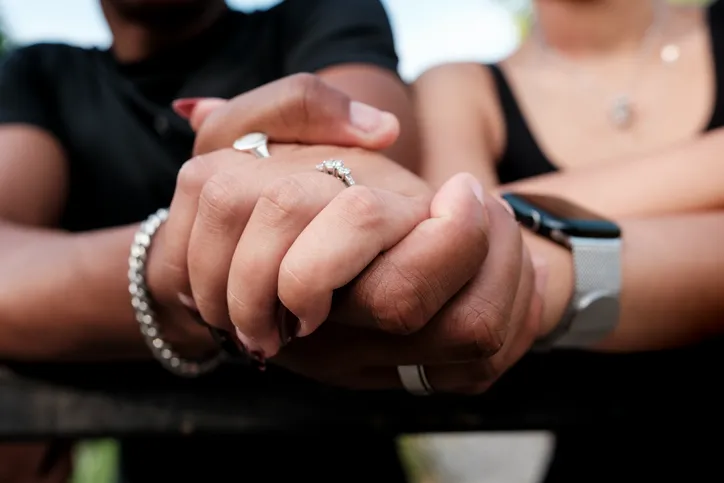 Pareja tomada de las manos con anillos, simbolizando el compromiso de una pareja de hecho