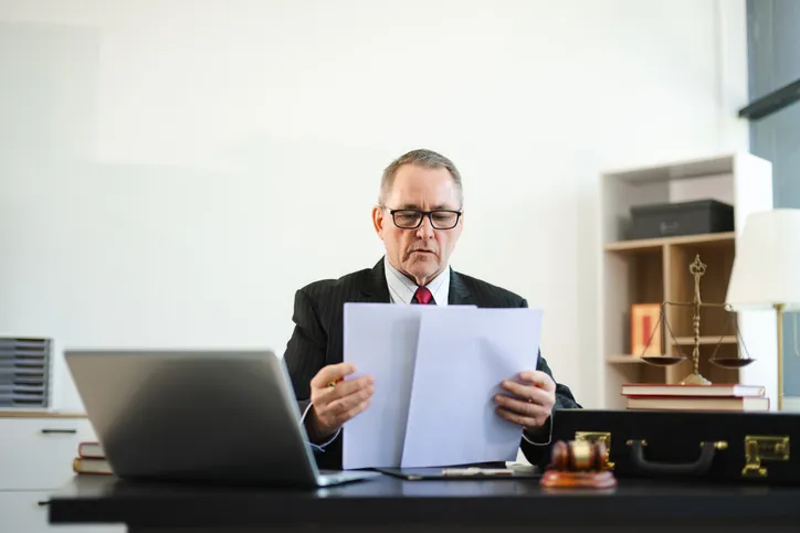Notario examinando una escritura o documento legal en su despacho