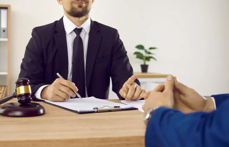 Reunión entre abogado y cliente para firmar un documento legal