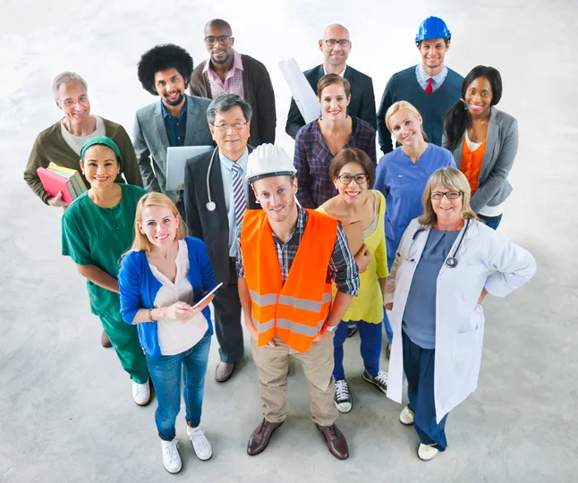 Grupo diverso de trabajadores de distintas profesiones, como sanidad, construcción, oficina y medicina, posando juntos y sonriendo.