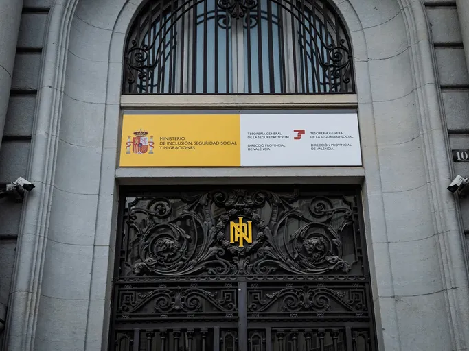Fachada de la sede de la Tesorería General de la Seguridad Social, Dirección Provincial de Valencia, con una puerta de hierro ornamentada.