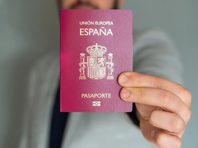 Hombre mostrando un pasaporte español de la Unión Europea frente a la cámara.