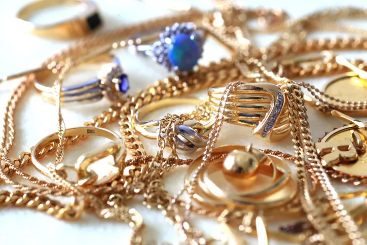 Conjunto de anillos, cadenas y joyas de oro amontonados, representando los bienes y objetos de valor incluidos en una herencia