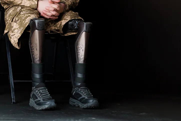 Persona militar sentada con prótesis en ambas piernas, ilustrando la incapacidad permanente