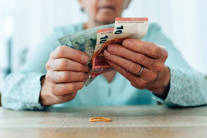 Persona mayor contando billetes de euro sobre una mesa, en referencia a la pensión de viudedad