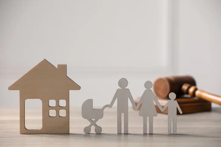 Figuras de una casa y una familia junto a un mazo de juez, representando un litigio hipotecario familiar