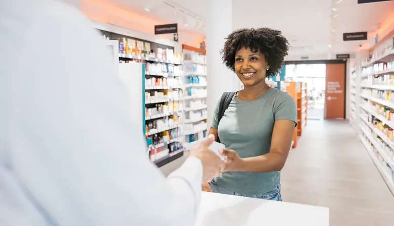 Mujer sonriente recibiendo un producto en el mostrador de una farmacia
