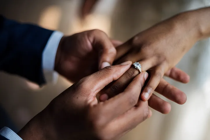 Un hombre colocando un anillo de compromiso en la mano de una mujer, representando el paso hacia el matrimonio