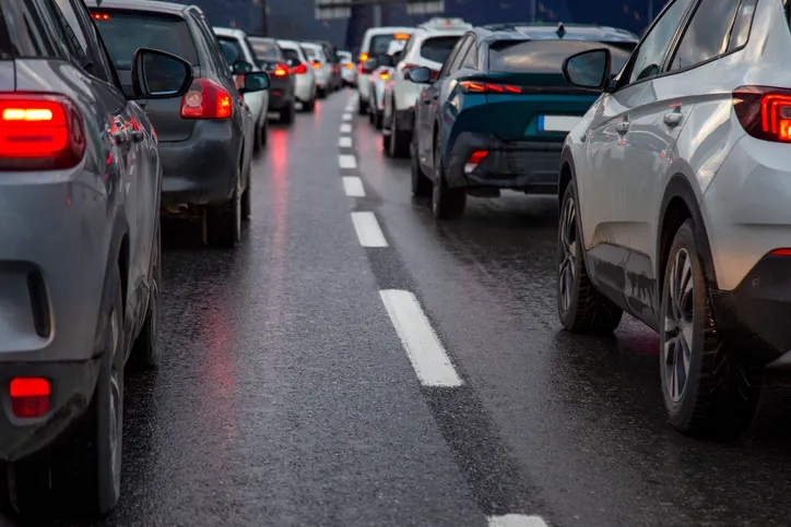 Fila de coches con las luces de freno encendidas en un atasco de tráfico en una carretera mojada