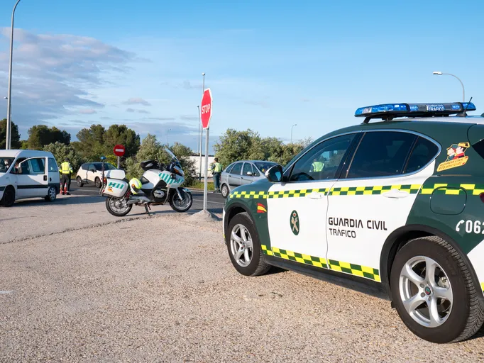 Vehículo y moto de la Guardia Civil de Tráfico realizando un control de carretera junto a una señal de stop