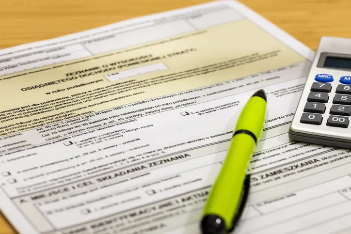 Formulario de declaración fiscal junto a una calculadora y un bolígrafo verde