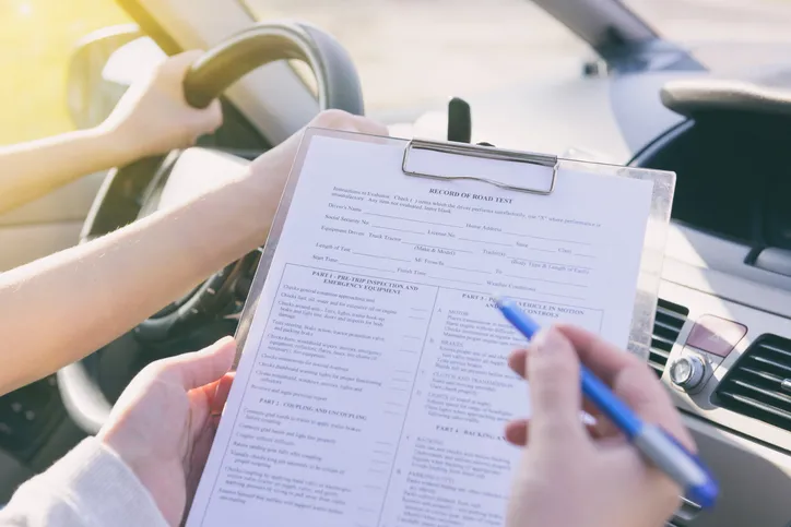 Examinador rellenando una plantilla de evaluación durante un examen práctico de conducir