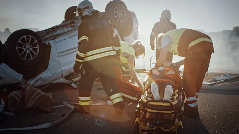 Equipo de bomberos y sanitarios atendiendo a una víctima junto a un coche volcado tras un accidente