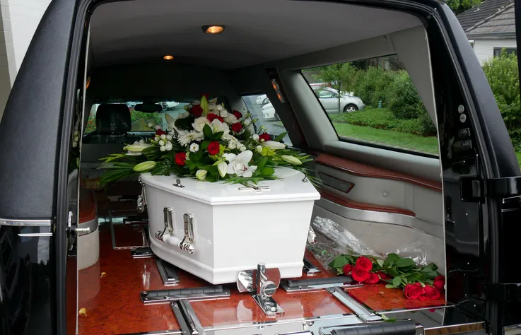 Ataúd blanco con flores en el interior de un coche fúnebre