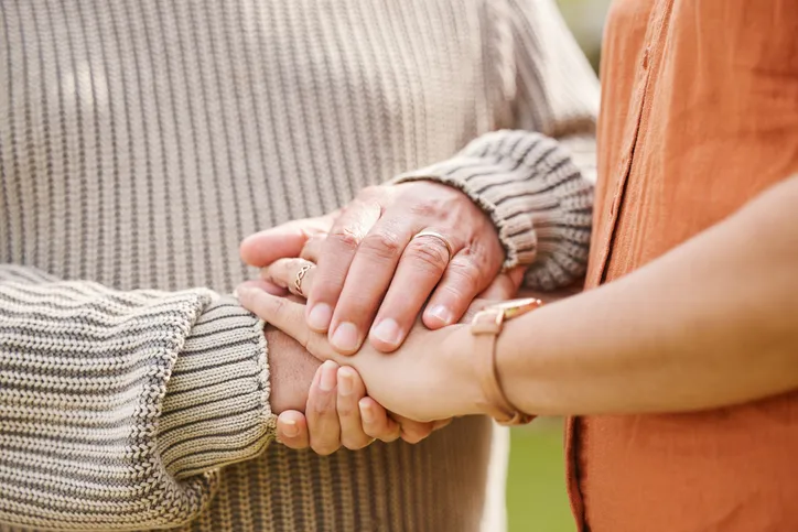Manos entrelazadas de dos personas en un gesto de consuelo y apoyo