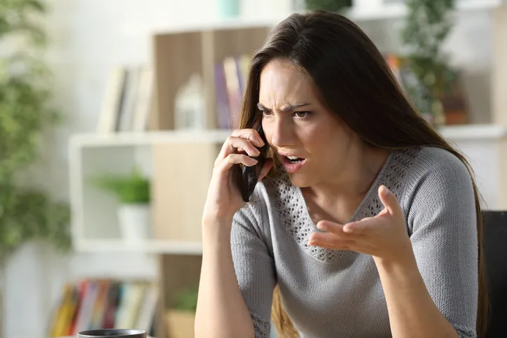Mujer enfadada hablando por teléfono con gesto de queja o reclamación