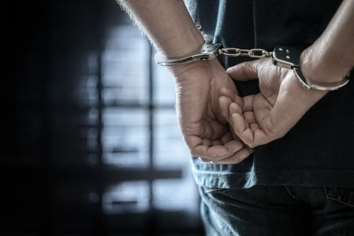 Persona con las manos esposadas a la espalda, simbolizando una detención por parte de las autoridades.