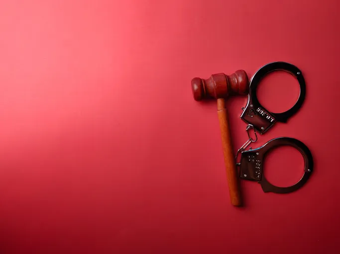 Mazo de juez y esposas sobre un fondo rojo, representando la justicia penal.
