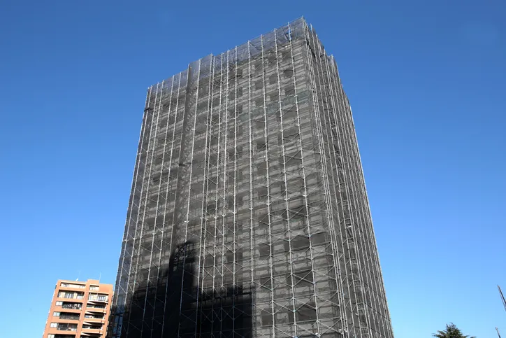 Edificio de gran altura cubierto de andamios durante unas obras de rehabilitación de fachada.