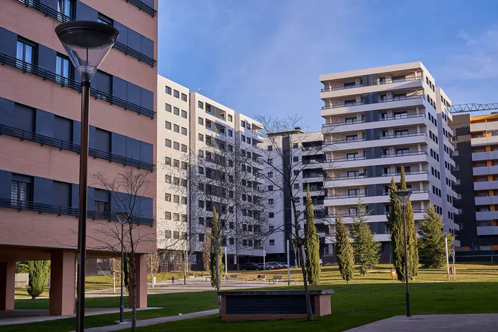 Conjunto de edificios residenciales modernos con zonas verdes y farolas, en una urbanización de bloques de pisos.